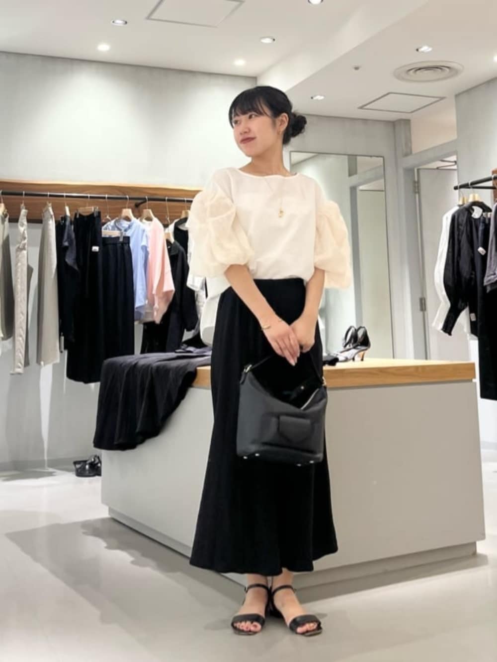 ブラック系のスカート、ホワイト系のシャツ/ブラウスを着用したレディースの夏コーディネートの8枚目の写真
