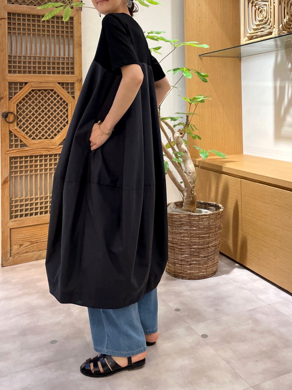 ブラック系のワンピース、ブルー系のデニムパンツを着用したレディースの春コーディネートの2枚目の写真