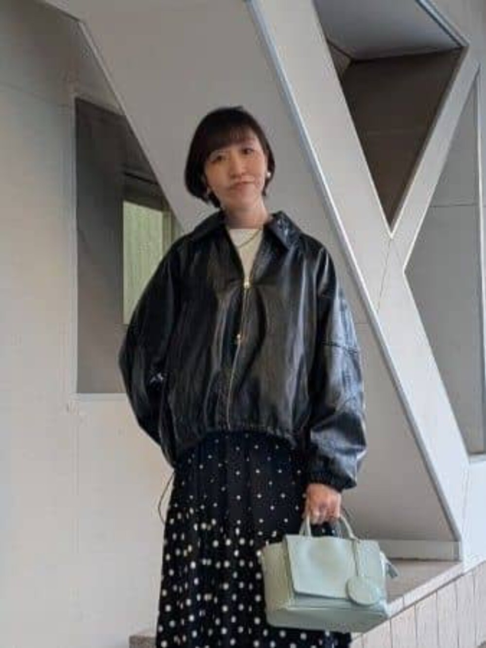 グリーン系のハンドバッグ、ブラック系のスカート、ブラック系のブルゾンを着用したレディースの冬コーディネートの4枚目の写真