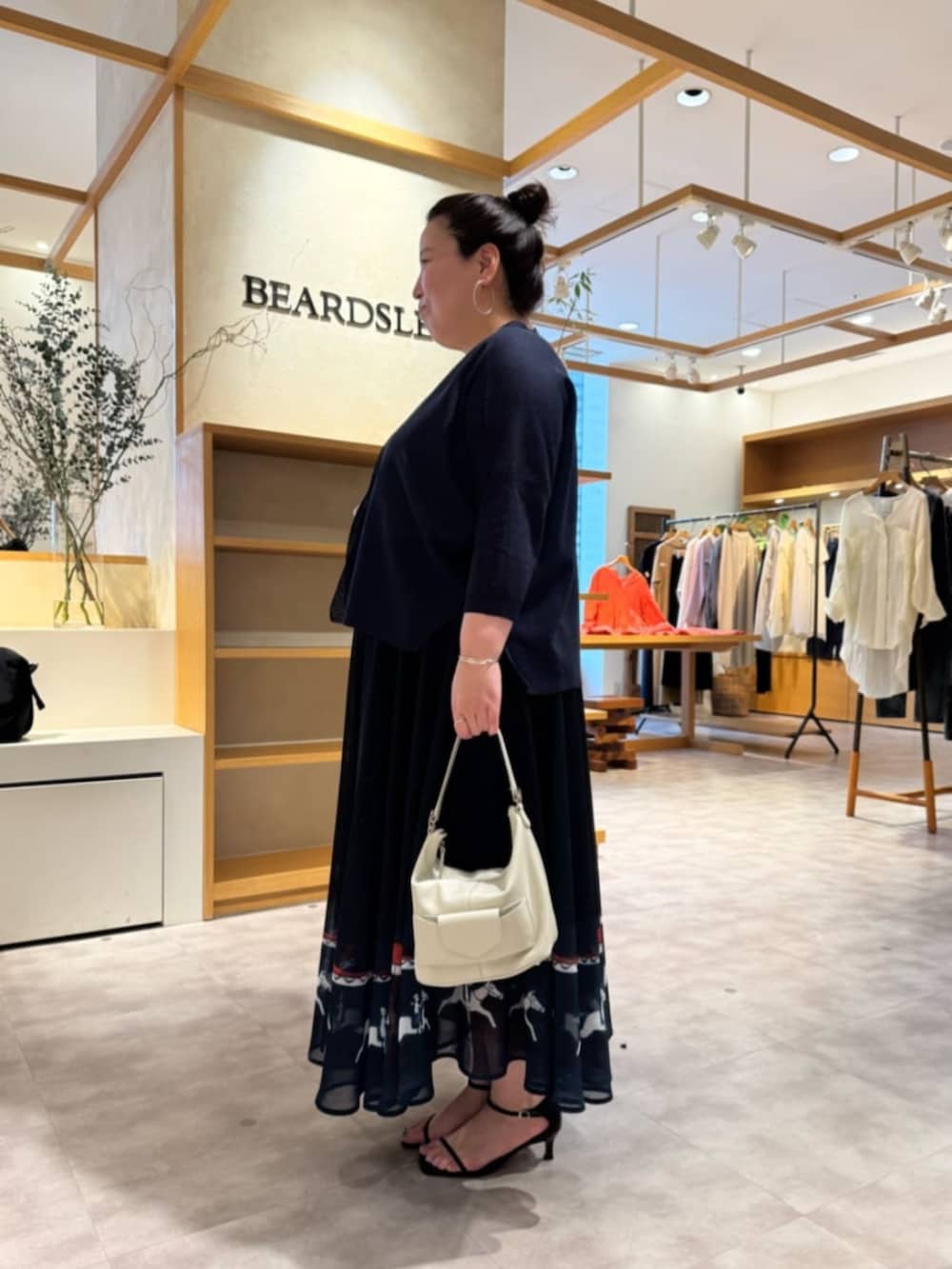 ホワイト系のトートバッグ、ブルー系のカーディガン/ボレロ、ブルー系のスカートを着用したレディースの春コーディネートの2枚目の写真