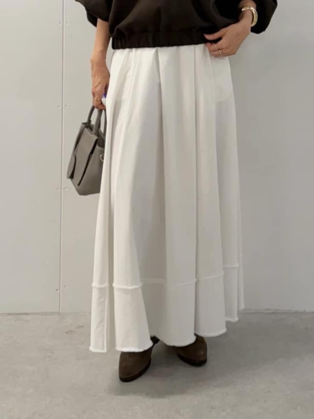 グレー系のハンドバッグ、ホワイト系のスカート、ブラウン系のTシャツ/カットソーを着用したレディースの夏コーディネートの8枚目の写真