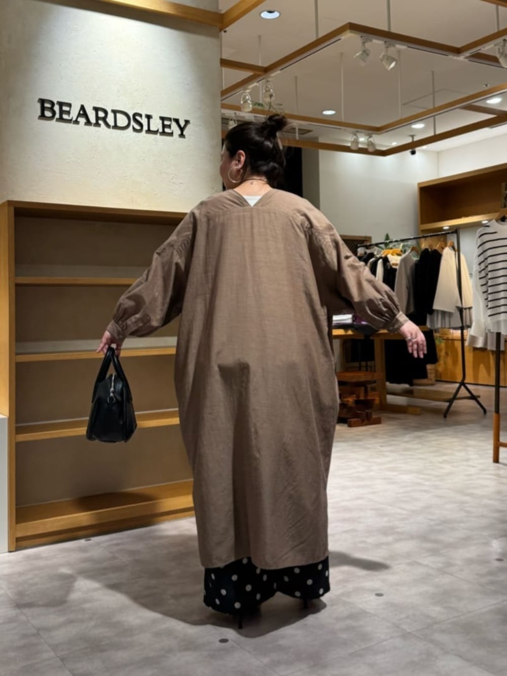 ブラック系のボストンバッグ、ベージュ系のワンピース、ブラック系のその他パンツを着用したレディースの冬コーディネートの5枚目の写真