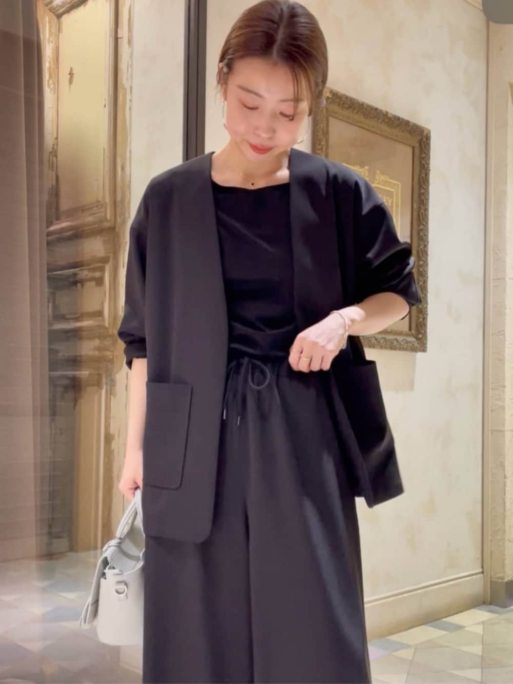 グリーン系のハンドバッグ、ブラック系のその他アウター、ブラック系のその他パンツを着用したレディースの冬コーディネートの5枚目の写真