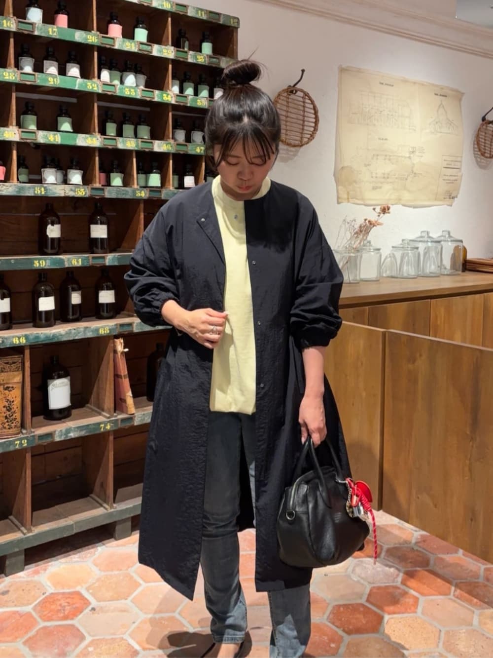 ブルー系のデニムパンツ、ブラック系のボストンバッグ、イエロー系のTシャツ/カットソーを着用したレディースの冬コーディネートの4枚目の写真