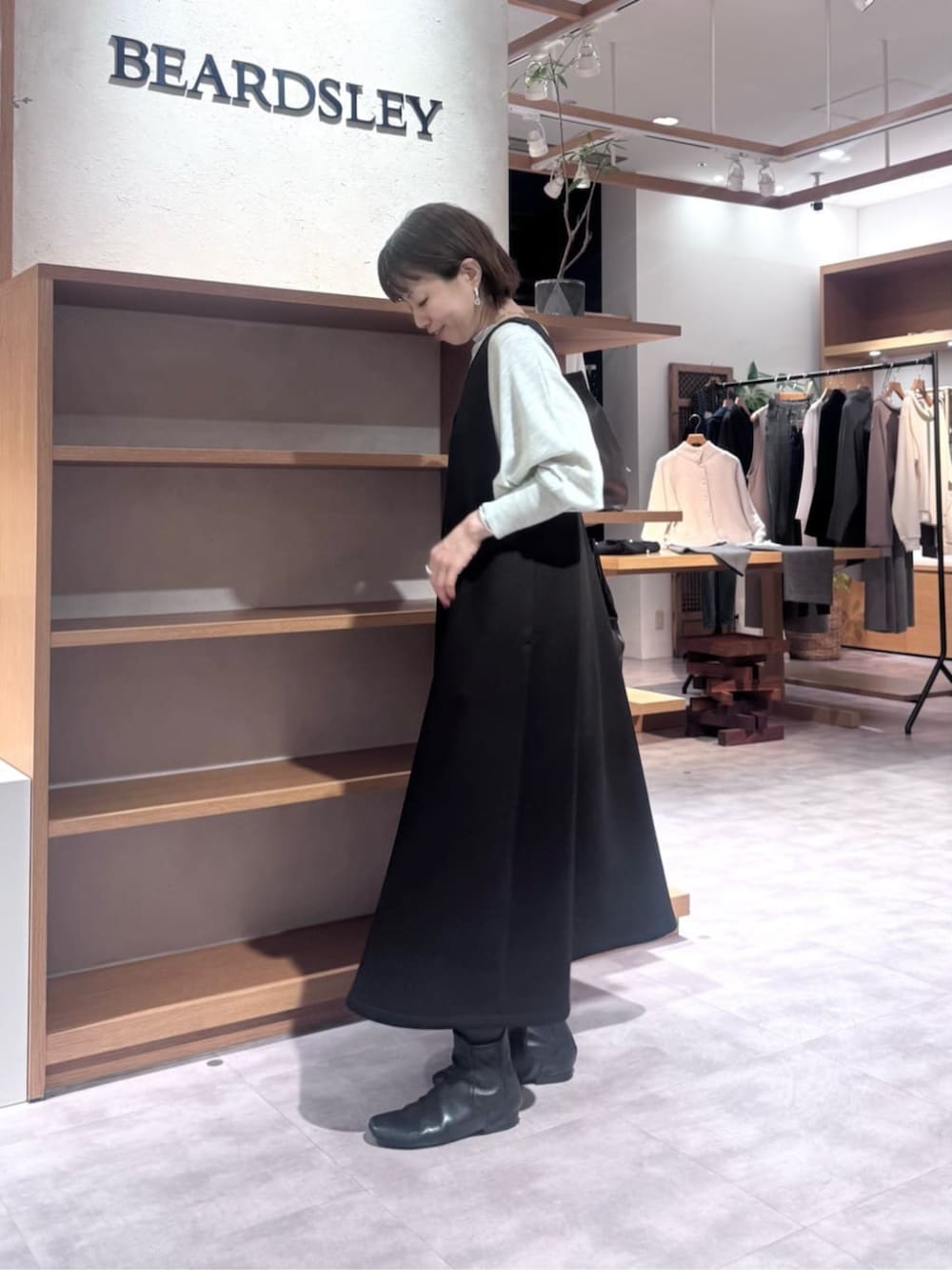 ブラック系のトートバッグ、ブラック系のジャンパースカート、ブラック系のダウンジャケット/コートを着用したレディースの冬コーディネートの6枚目の写真