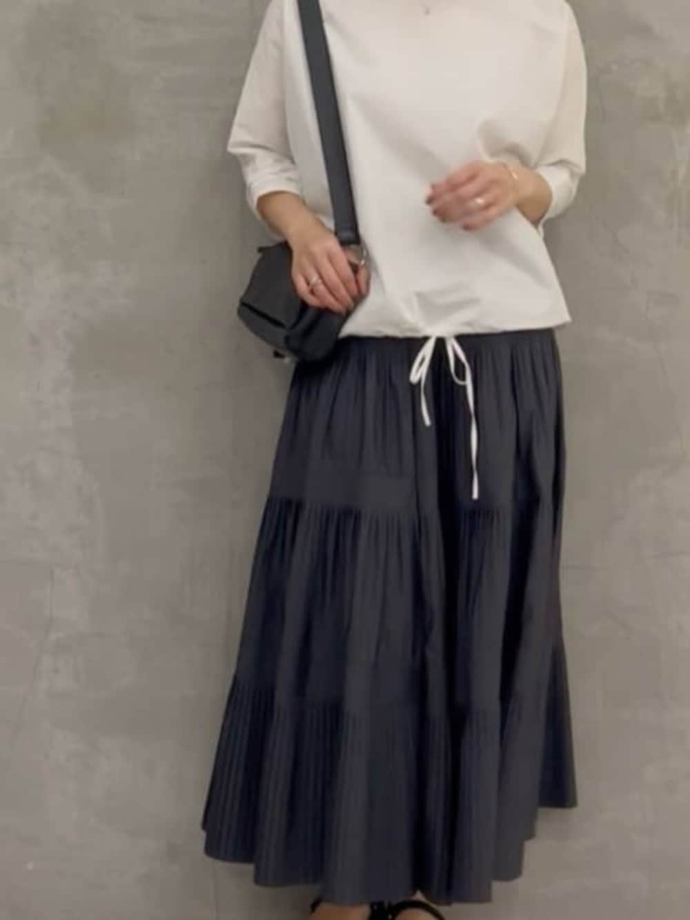 グレー系のスカート、ブラック系のショルダーバッグ、ホワイト系のシャツ/ブラウスを着用したレディースの春コーディネートの6枚目の写真