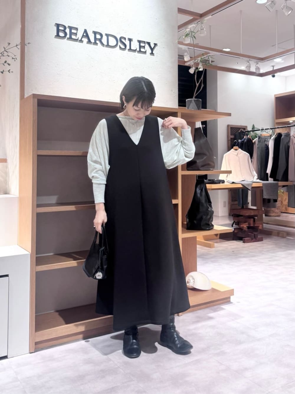 ブラック系のトートバッグ、ブラック系のジャンパースカート、ブラック系のダウンジャケット/コートを着用したレディースの冬コーディネートの5枚目の写真