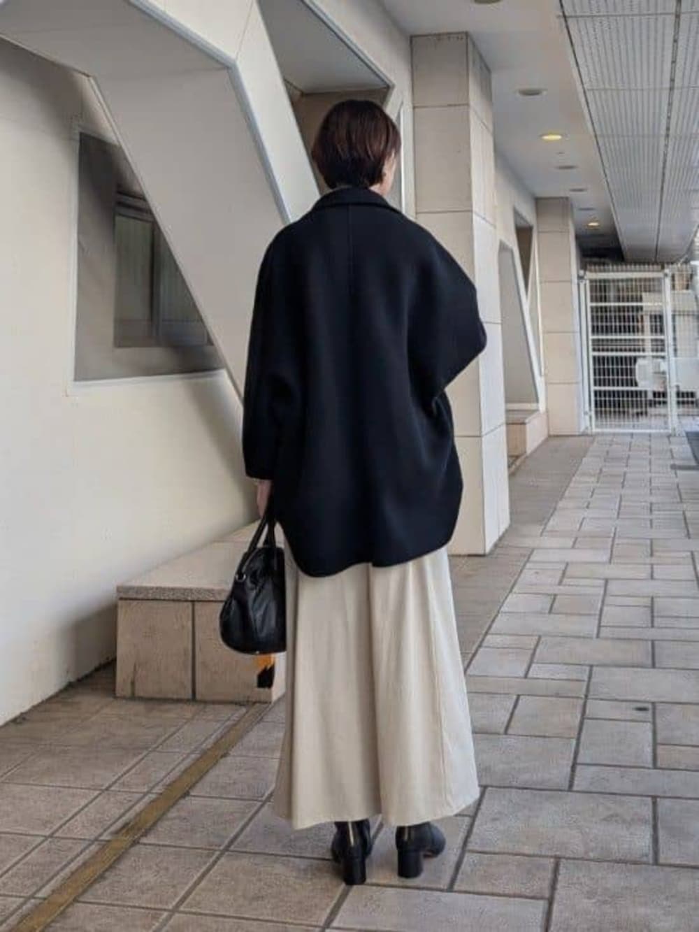 ブラック系のトートバッグ、ブラック系のその他アウター、ベージュ系のスカートを着用したレディースの夏コーディネートの3枚目の写真