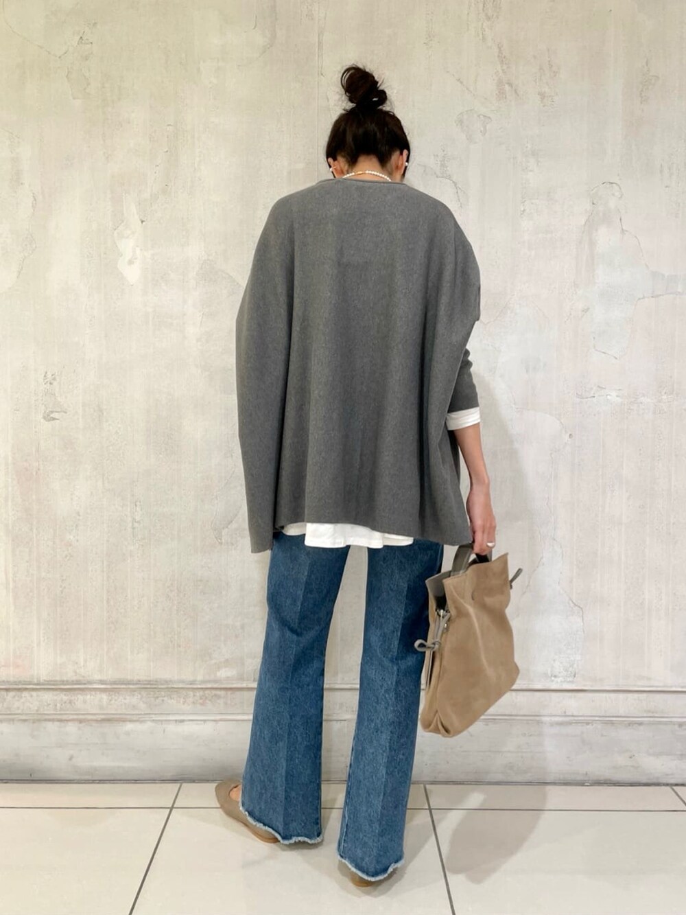 グレー系のニット/セーター、ブルー系のデニムパンツ、ブラウン系のショルダーバッグを着用したレディースの秋コーディネートの3枚目の写真