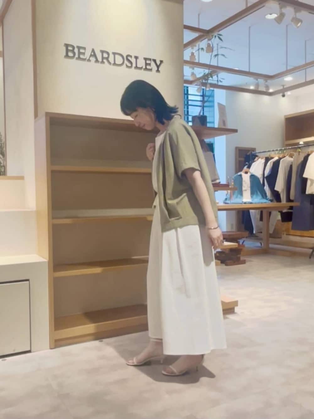 ブラック系のショルダーバッグ、ホワイト系のその他パンツ、グリーン系のベストを着用したレディースの春コーディネートの2枚目の写真