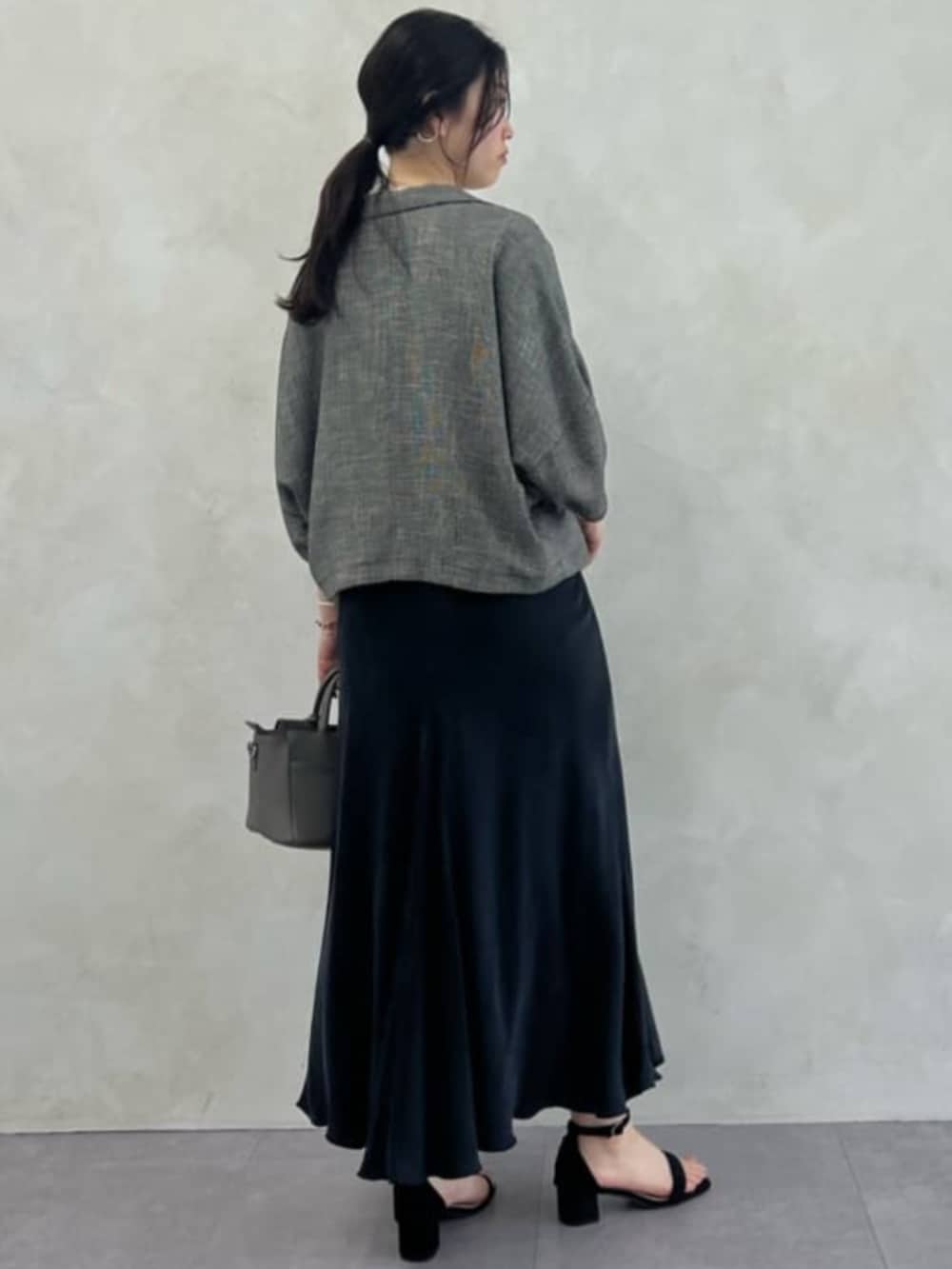 ブラック系のスカート、グレー系のハンドバッグ、ベージュ系のテーラードジャケットを着用したレディースの春コーディネートの2枚目の写真