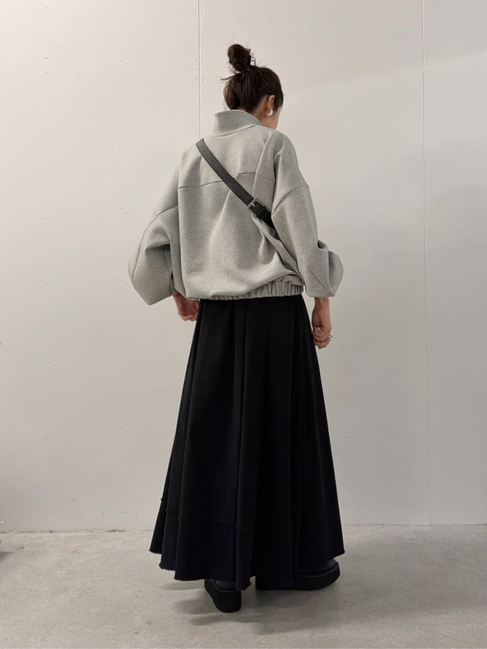ブラック系のショルダーバッグ、ブラック系のスカート、グレー系のTシャツ/カットソーを着用したレディースの夏コーディネートの3枚目の写真