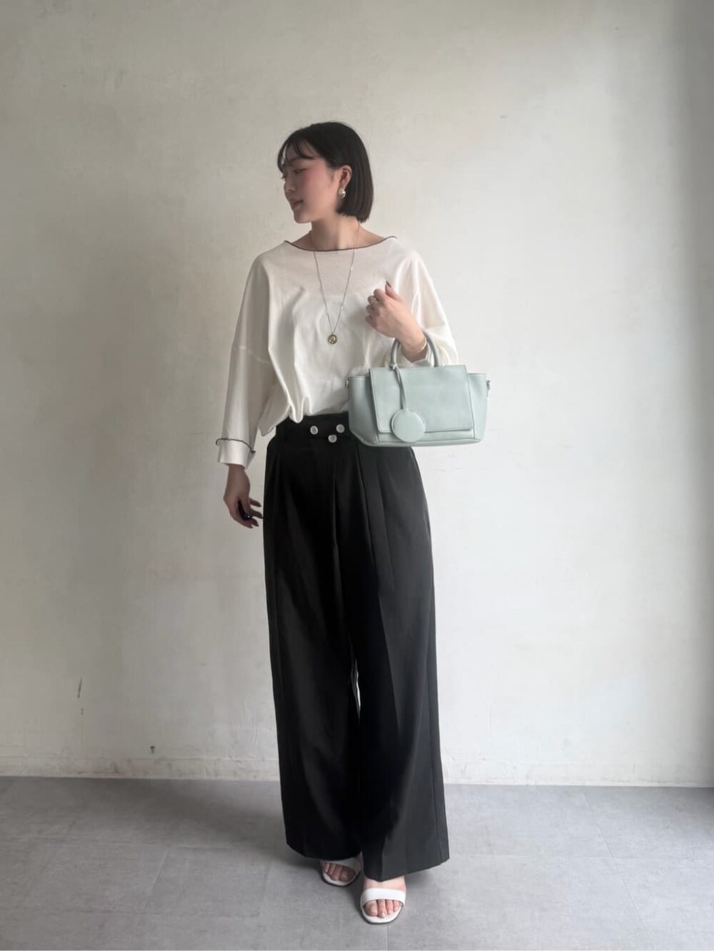 グリーン系のハンドバッグ、グレー系のその他パンツ、ホワイト系のTシャツ/カットソーを着用したレディースの冬コーディネートの2枚目の写真