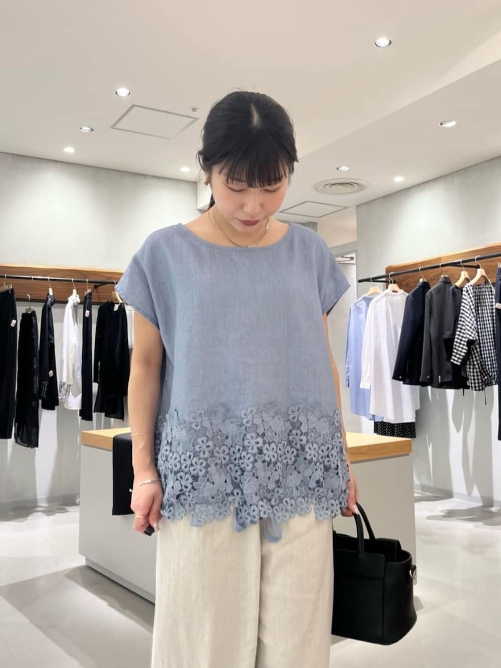 ブラック系のハンドバッグ、ベージュ系のその他パンツ、ブルー系のシャツ/ブラウスを着用したレディースの夏コーディネートの6枚目の写真