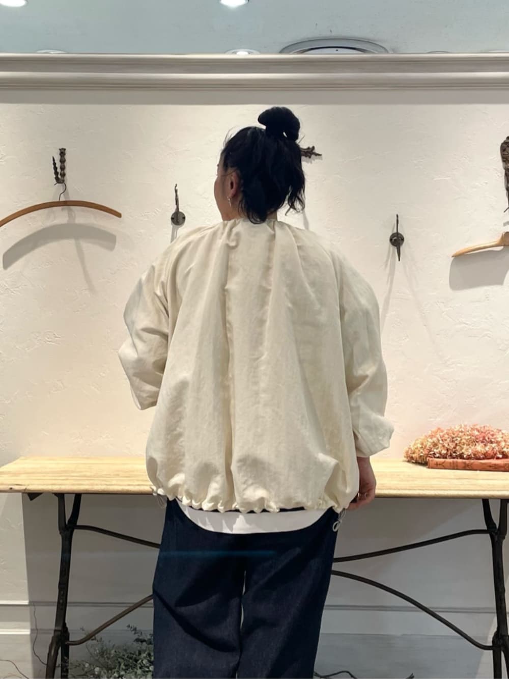 ホワイト系のノーカラージャケット、ホワイト系のニット/セーター、ブルー系のデニムパンツを着用したレディースの冬コーディネートの6枚目の写真