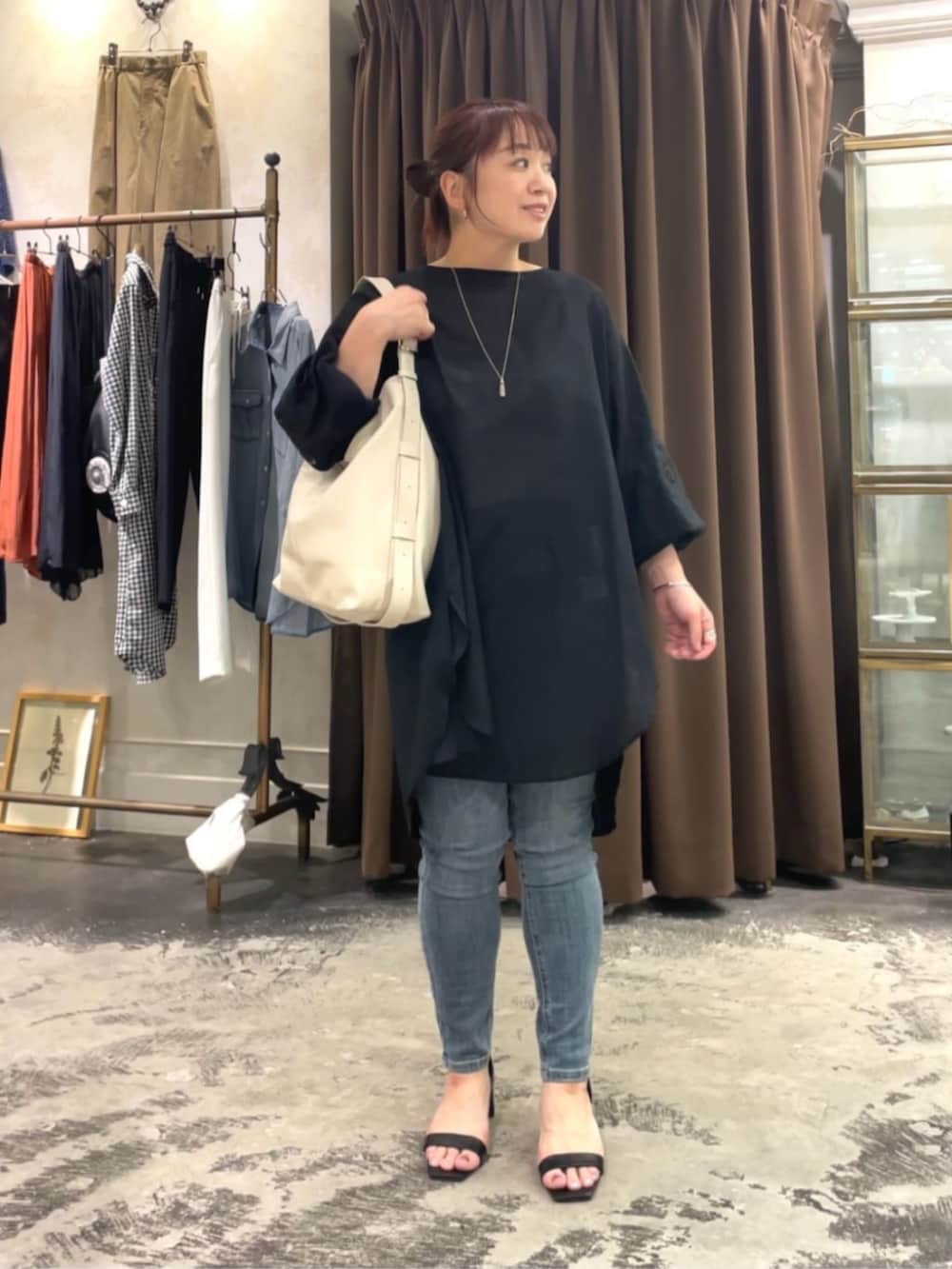 ブルー系のデニムパンツ、ホワイト系のショルダーバッグ、ブラック系のシャツ/ブラウスを着用したレディースの春コーディネートの2枚目の写真