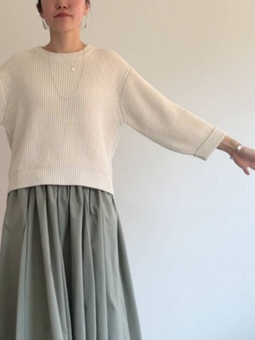 グリーン系のスカート、ホワイト系のニット/セーターを着用したレディースの冬コーディネートの6枚目の写真