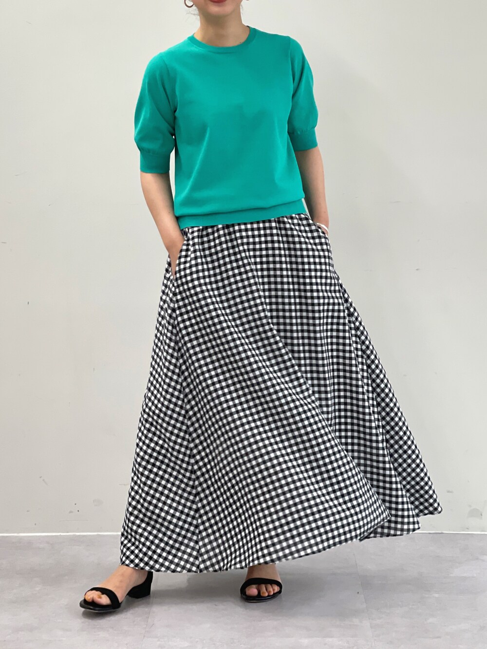 グリーン系のニット/セーター、ホワイト系のスカートを着用したレディースの夏コーディネートの2枚目の写真