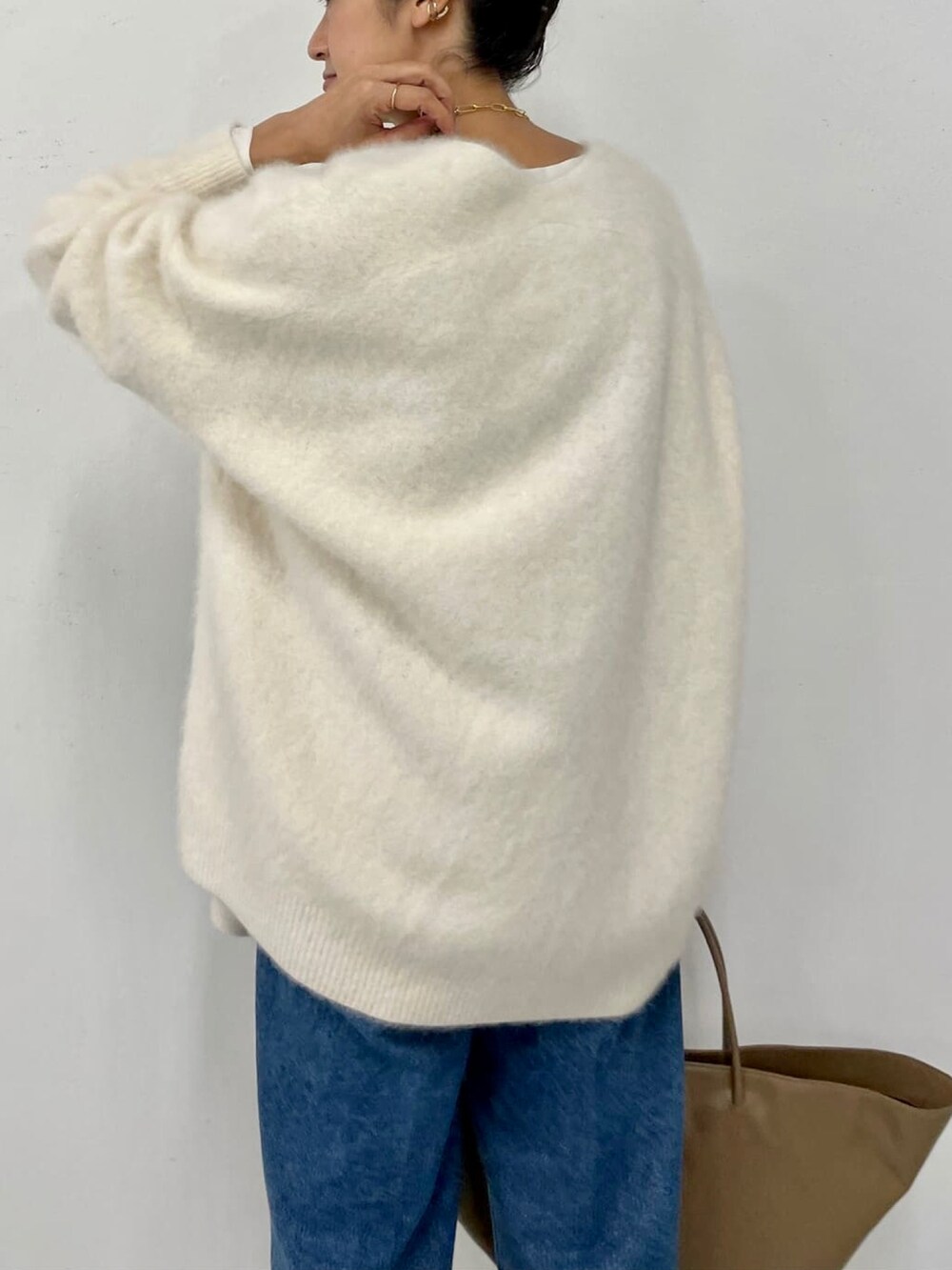 ホワイト系のカーディガン/ボレロ、ホワイト系のシャツ/ブラウス、ブルー系のデニムパンツを着用したレディースの秋コーディネートの3枚目の写真