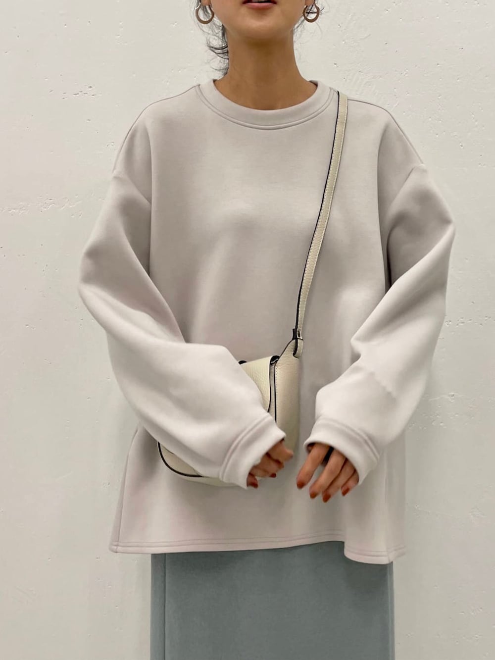 ベージュ系のTシャツ/カットソー、グリーン系のスカート、ホワイト系のショルダーバッグを着用したレディースの秋コーディネートの3枚目の写真