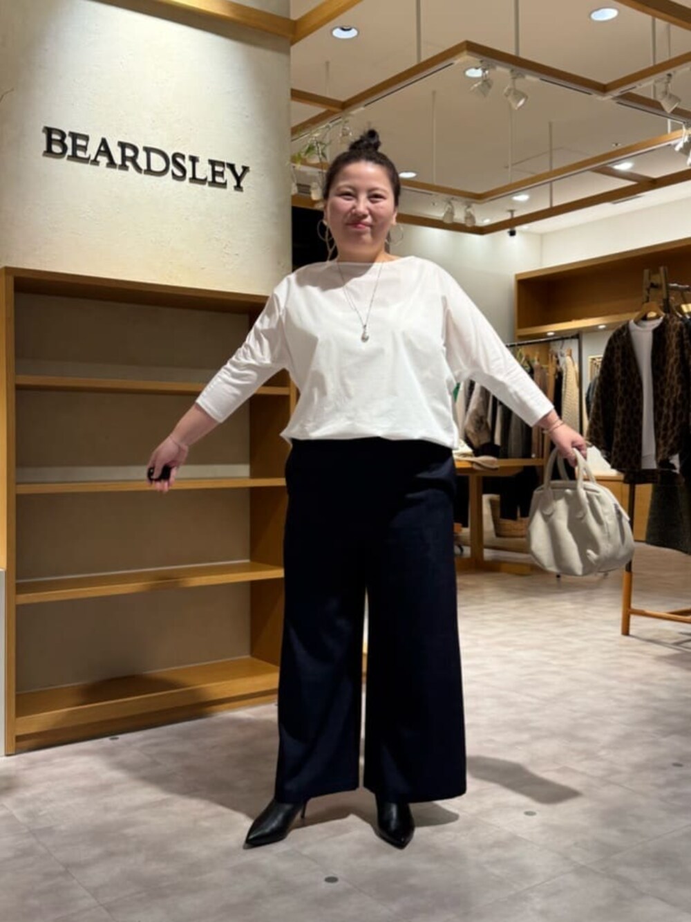 グレー系のボストンバッグ、ブラック系のブーツ、ホワイト系のシャツ/ブラウスを着用したレディースの冬コーディネートの3枚目の写真