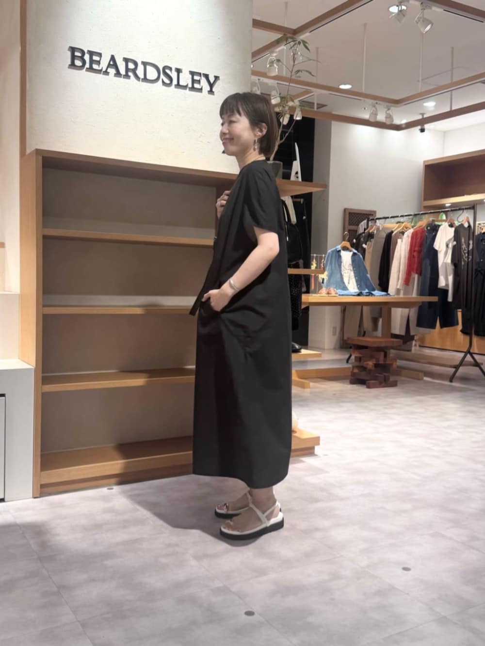 ブラック系のショルダーバッグ、ホワイト系のサンダル、ブラック系のワンピースを着用したレディースの春コーディネートの4枚目の写真