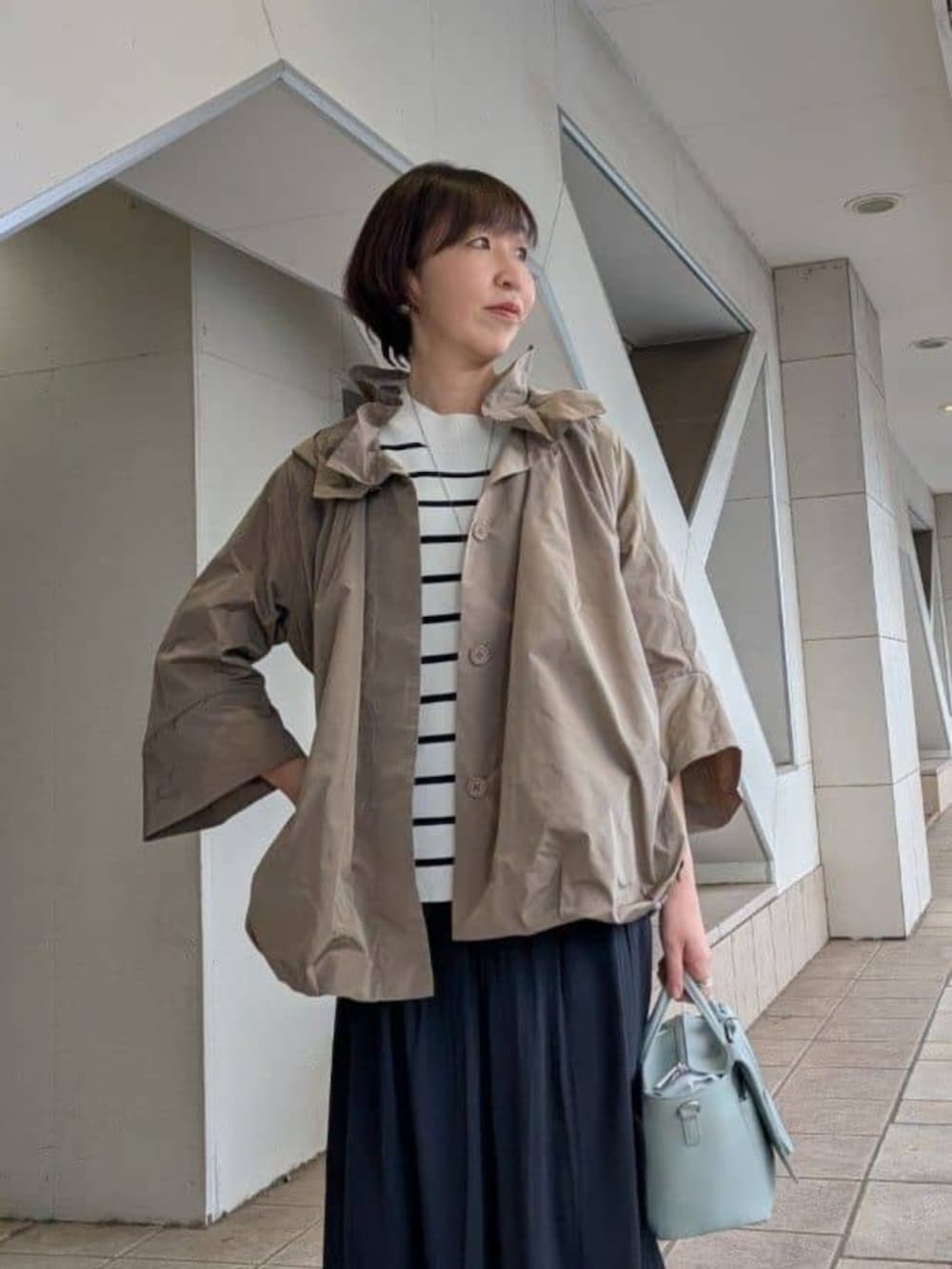 グリーン系のハンドバッグ、ブラック系のその他パンツ、ブラウン系のブルゾンを着用したレディースの冬コーディネートの4枚目の写真