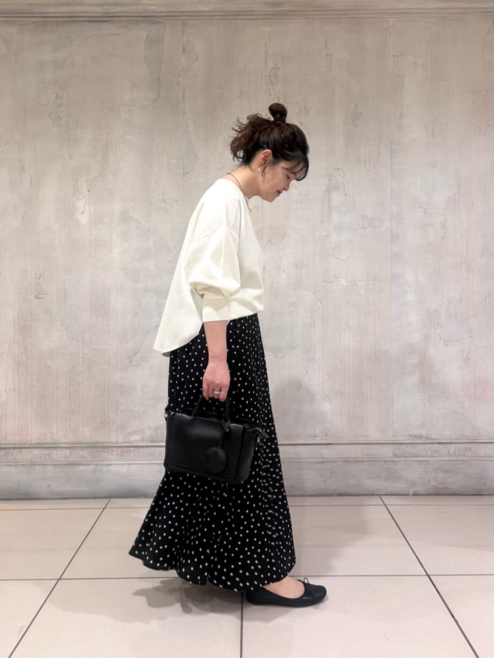 ブラック系のハンドバッグ、ブラック系のスカート、ホワイト系のTシャツ/カットソーを着用したレディースの春コーディネートの4枚目の写真