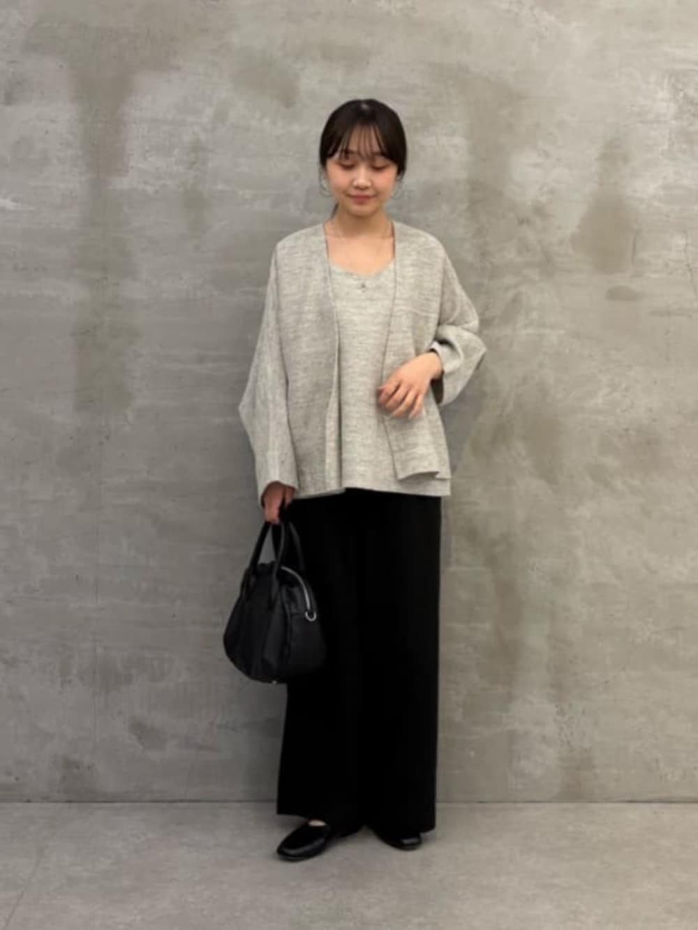 ブラック系のボストンバッグ、グレー系のニット/セーター、グレー系のカーディガン/ボレロを着用したレディースの春コーディネートの2枚目の写真