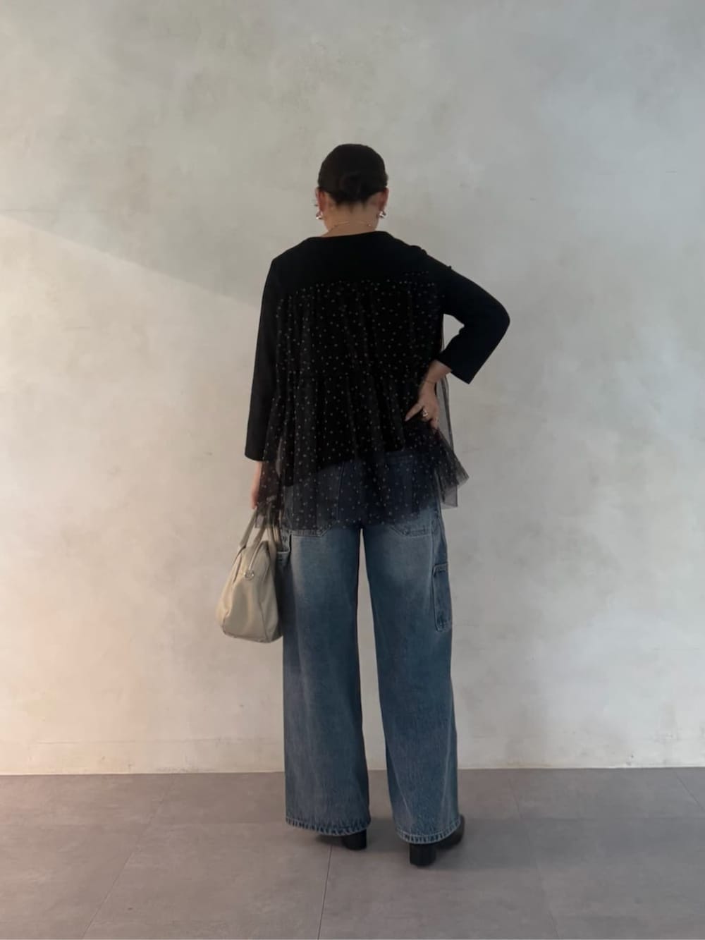 グレー系のボストンバッグ、ブラック系のTシャツ/カットソー、ブルー系のデニムパンツを着用したレディースの夏コーディネートの3枚目の写真