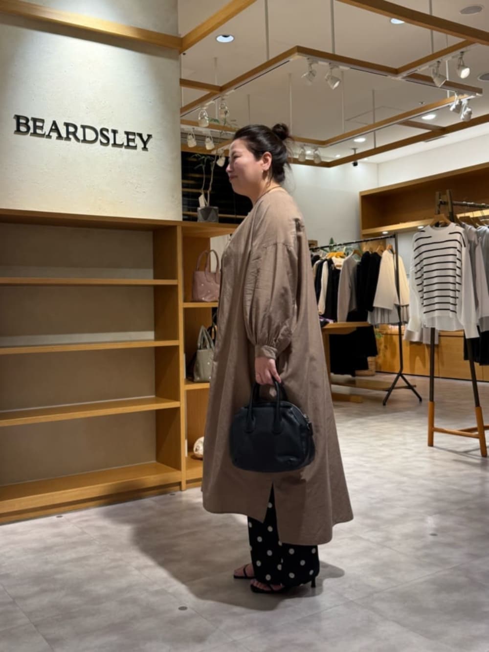 ブラック系のボストンバッグ、ベージュ系のワンピース、ブラック系のその他パンツを着用したレディースの冬コーディネートの2枚目の写真