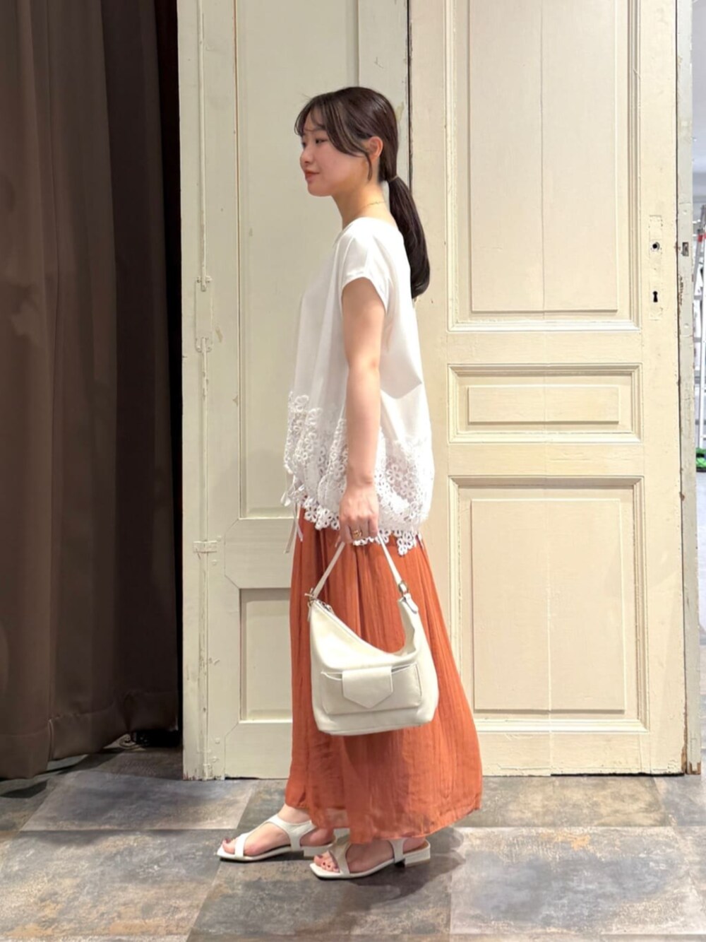 ホワイト系のトートバッグ、オレンジ系のその他パンツ、ホワイト系のTシャツ/カットソーを着用したレディースの春コーディネートの2枚目の写真