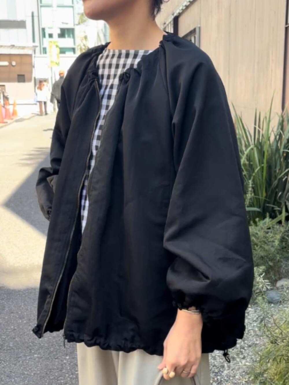グレー系のボストンバッグ、ブラック系のノーカラージャケット、ブラック系のシャツ/ブラウスを着用したレディースの春コーディネートの6枚目の写真
