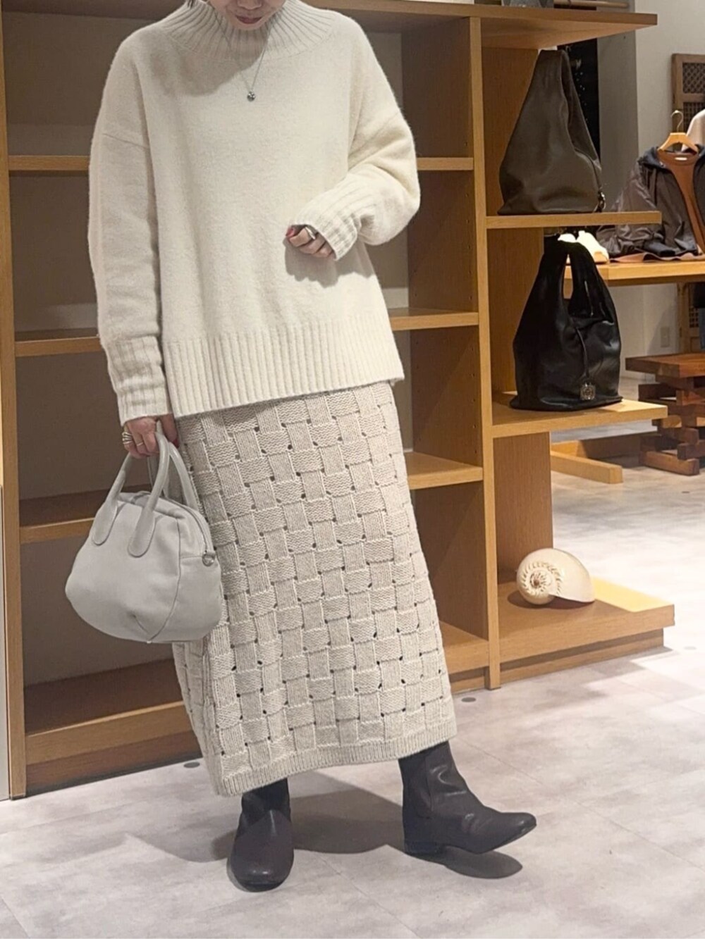 グレー系のボストンバッグ、ベージュ系のスカート、ブラウン系のダウンジャケット/コートを着用したレディースの冬コーディネートの9枚目の写真