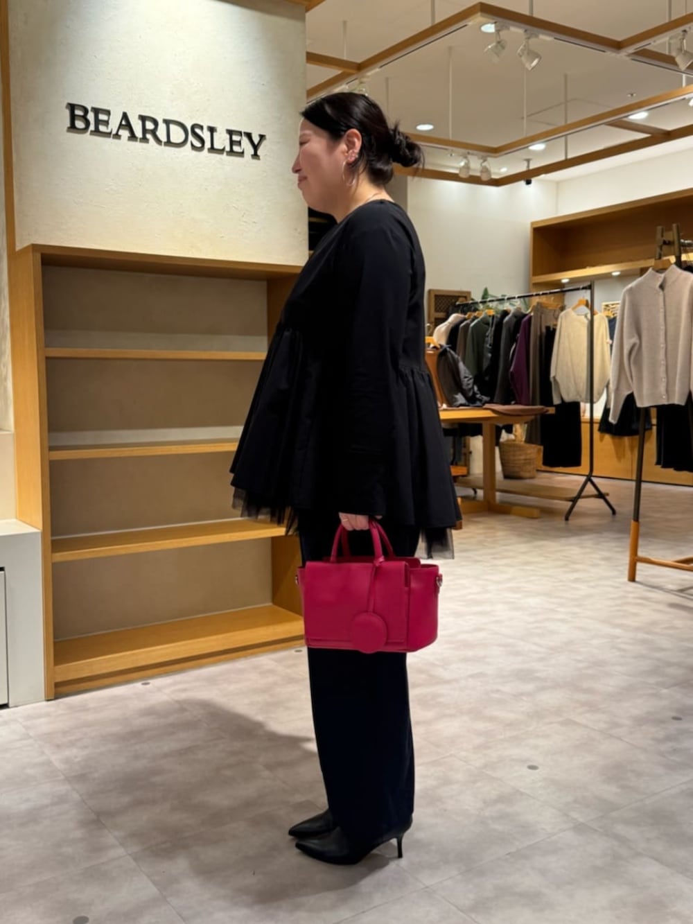 ピンク系のハンドバッグ、ブラック系のブーツ、ブラック系のブルゾンを着用したレディースの冬コーディネートの9枚目の写真