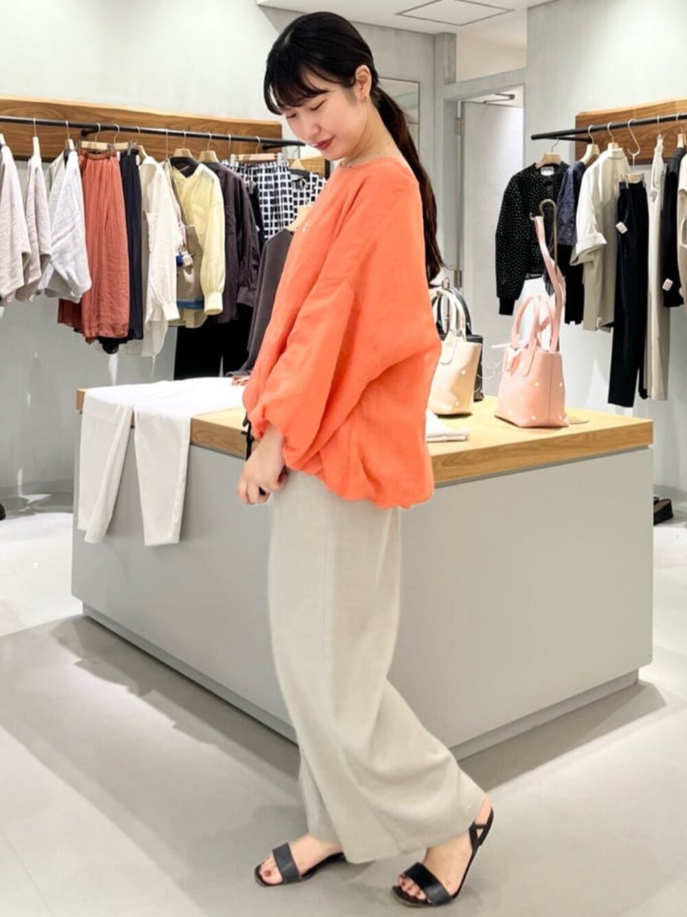 グレー系のその他パンツ、オレンジ系のシャツ/ブラウスを着用したレディースの春コーディネートの3枚目の写真