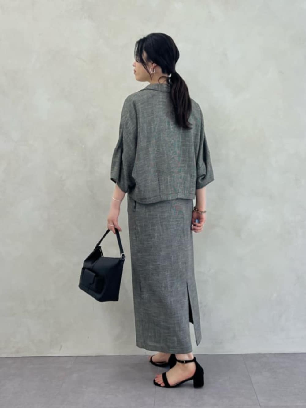 ブラック系のトートバッグ、ベージュ系のテーラードジャケット、ベージュ系のスカートを着用したレディースの春コーディネートの3枚目の写真