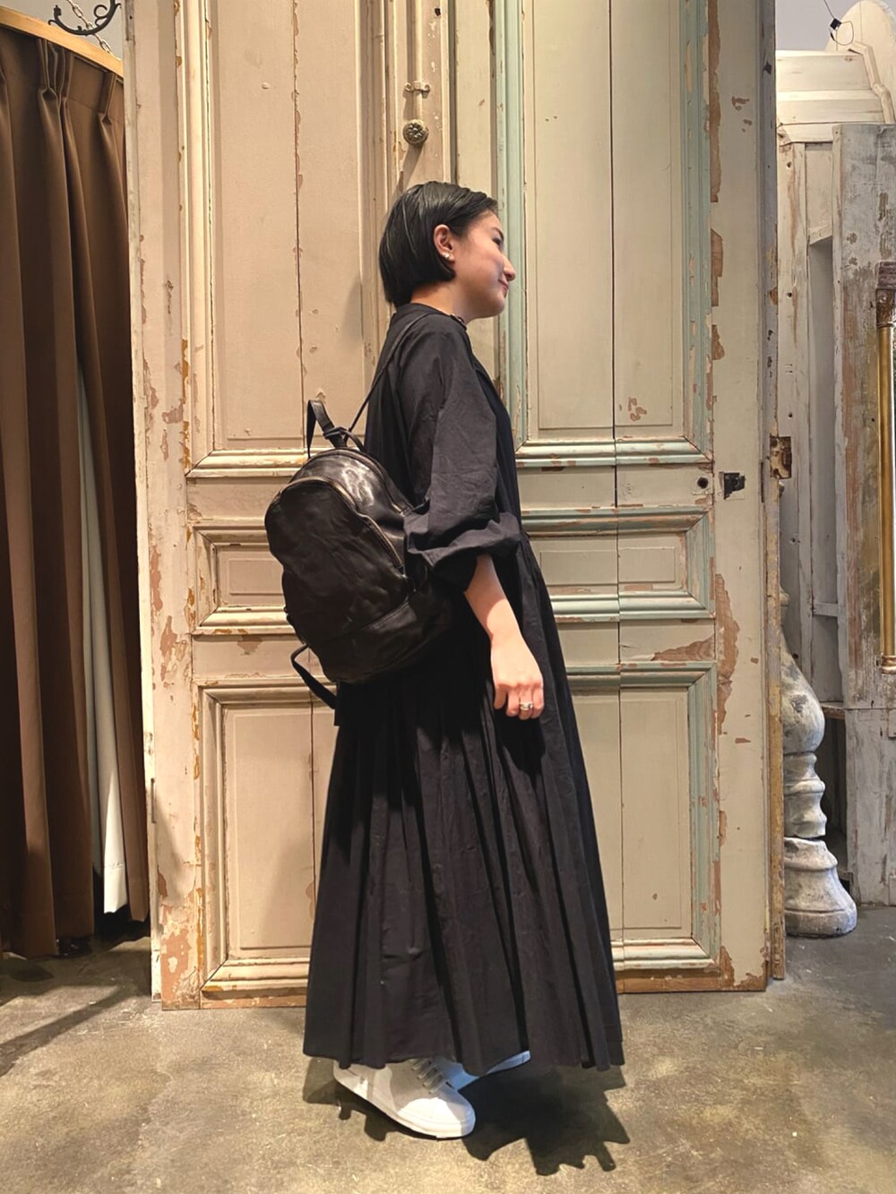 ブラック系のワンピース、ブラック系のトートバッグ、ホワイト系のスニーカーを着用したレディースの冬コーディネートの2枚目の写真