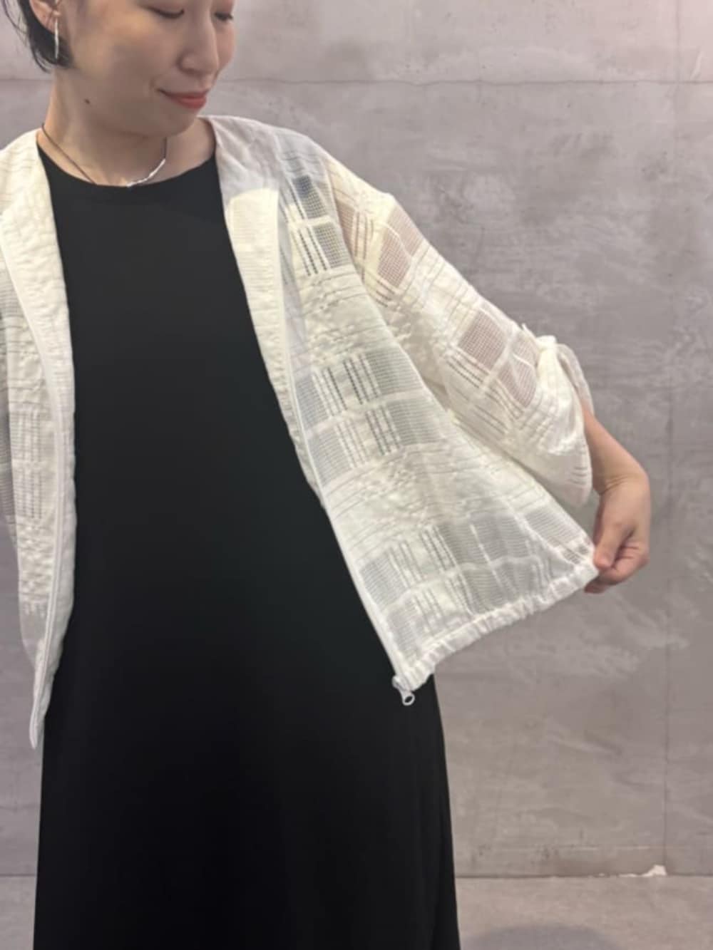 グレー系のハンドバッグ、ブラック系のワンピース、ホワイト系のブルゾンを着用したレディースの夏コーディネートの6枚目の写真