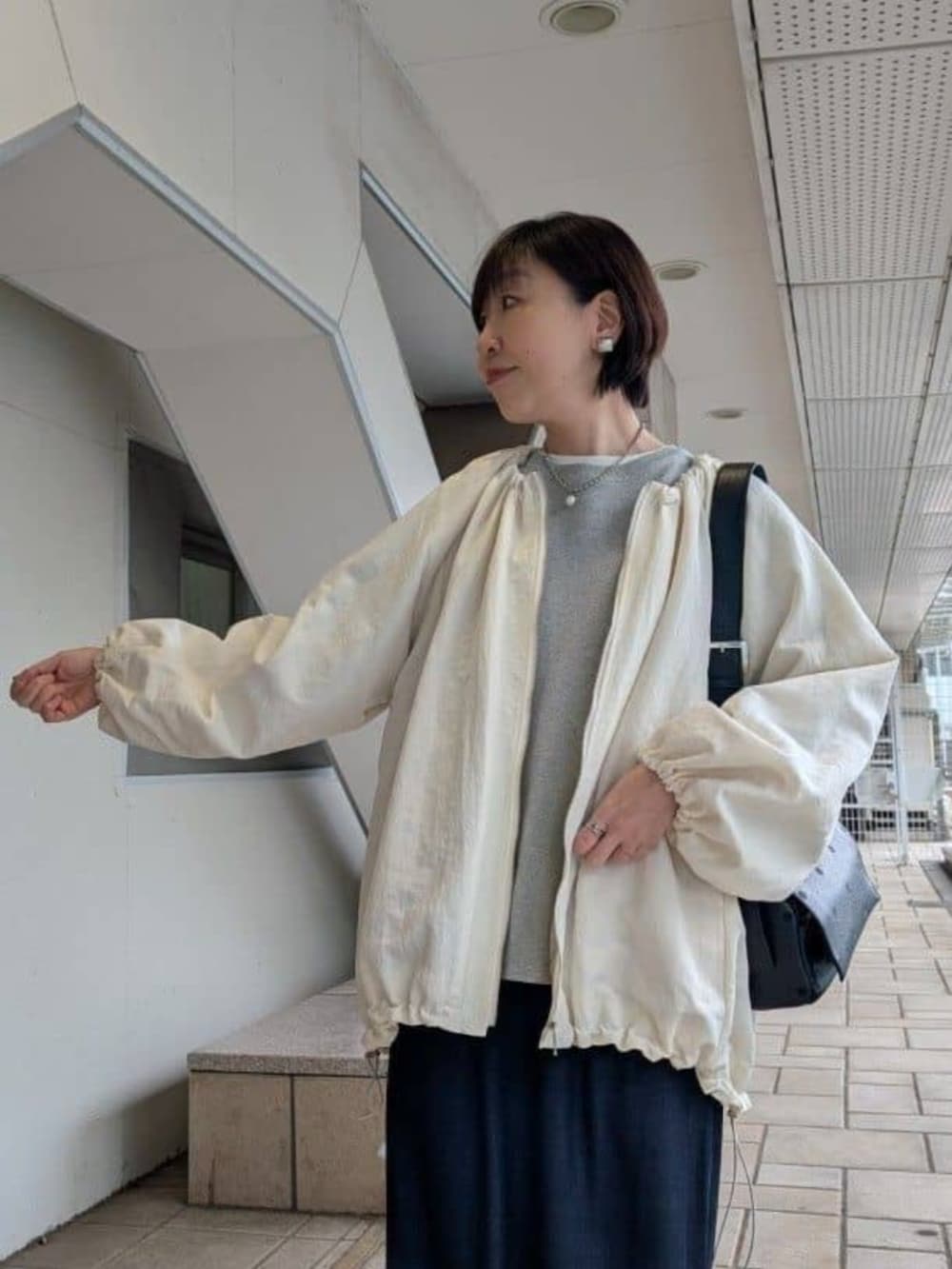 ブルー系のその他パンツ、グレー系のニット/セーター、ホワイト系のノーカラージャケットを着用したレディースの冬コーディネートの4枚目の写真