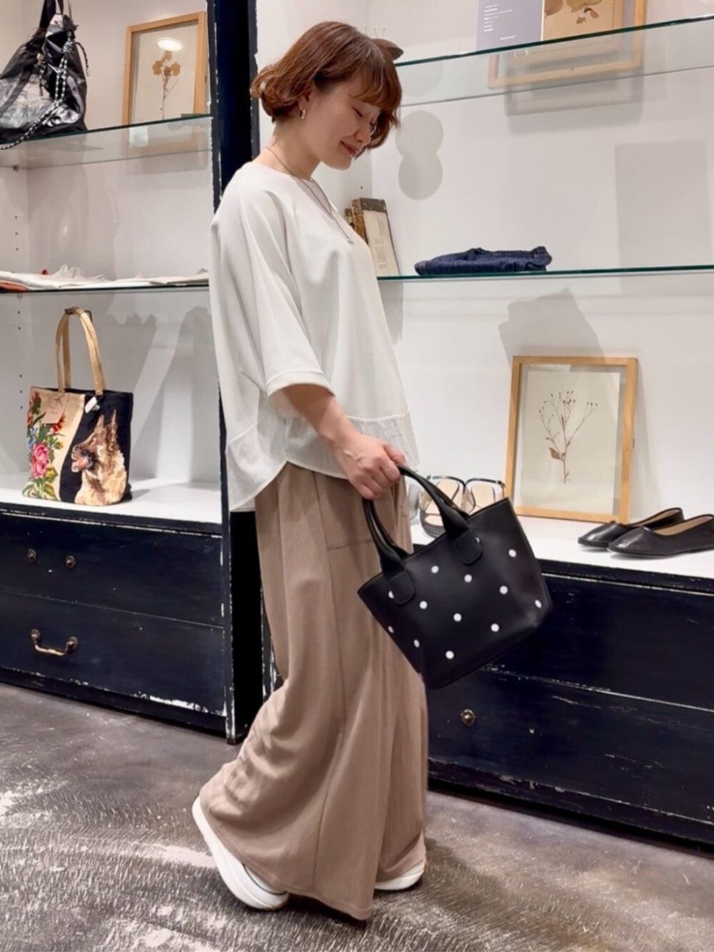 ベージュ系のその他パンツ、ブラック系のトートバッグ、ホワイト系のTシャツ/カットソーを着用したレディースの春コーディネートの2枚目の写真