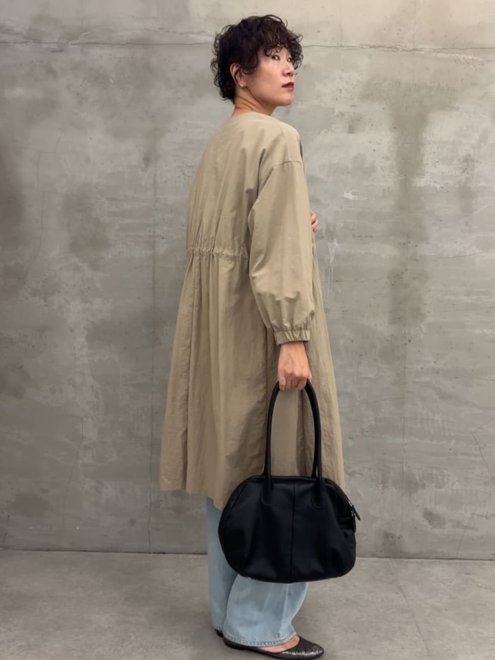 ベージュ系のその他アウター、ブラック系のボストンバッグ、ブルー系のデニムパンツを着用したレディースの冬コーディネートの3枚目の写真