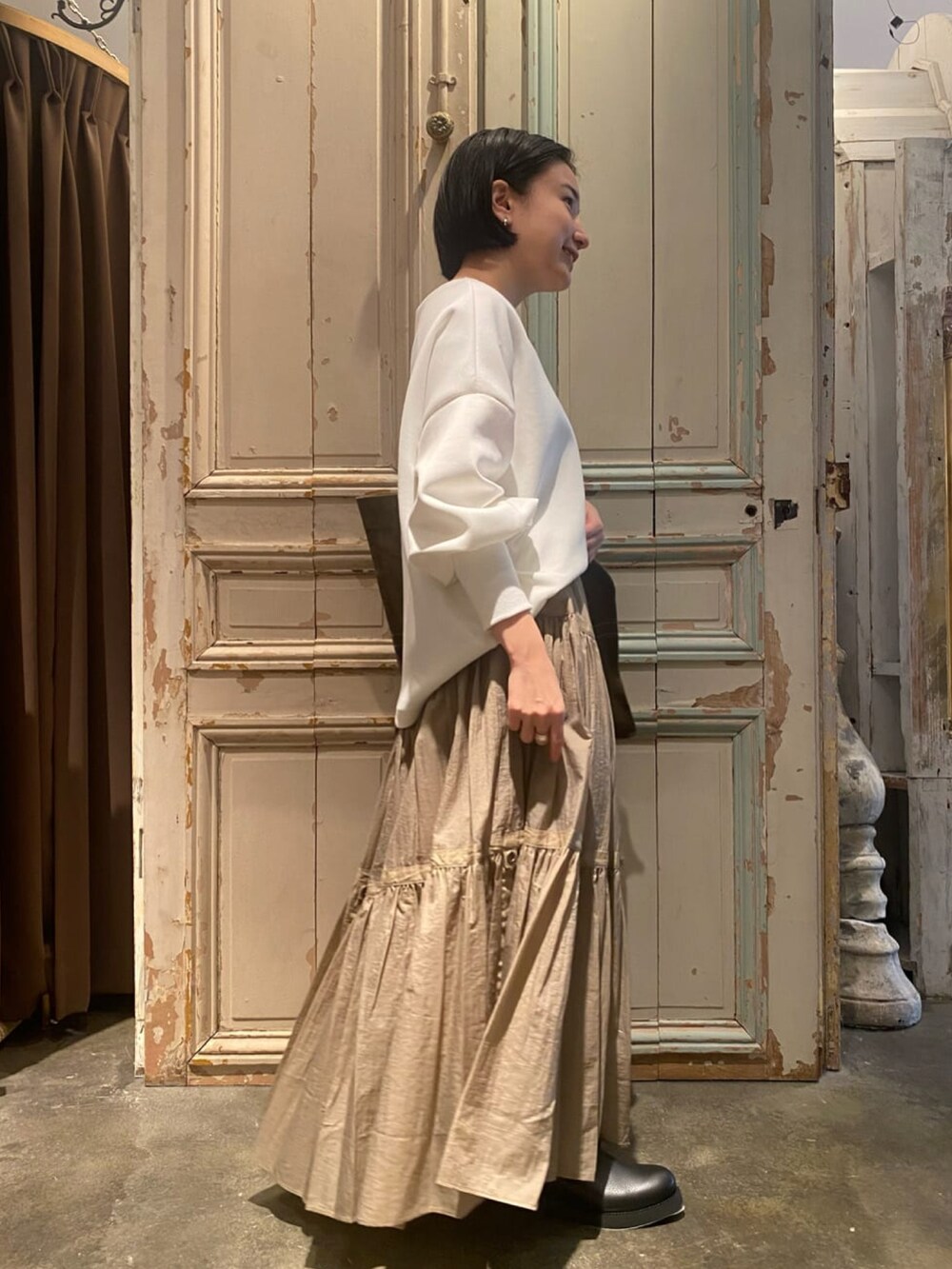 ベージュ系のスカート、ホワイト系のTシャツ/カットソー、グリーン系のトートバッグを着用したレディースの冬コーディネートの2枚目の写真