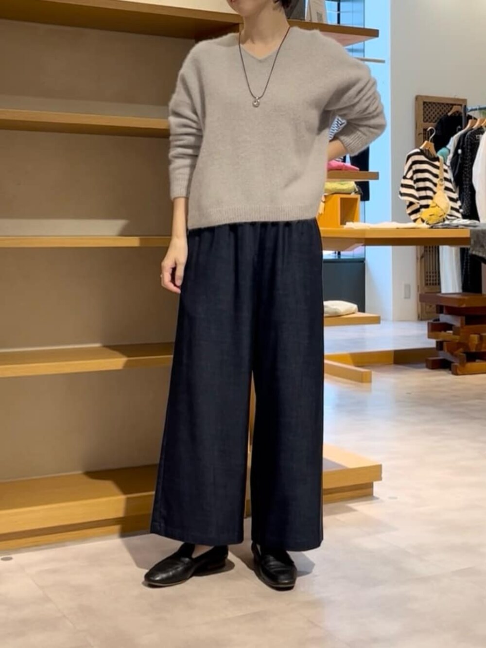 ブルー系のその他パンツ、グレー系のニット/セーター、ブラック系のダウンジャケット/コートを着用したレディースの冬コーディネートの9枚目の写真