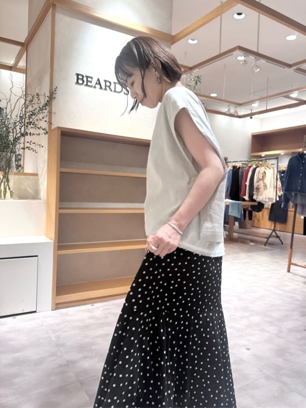 ブラック系のハンドバッグ、ブラック系のスカート、ベージュ系のシャツ/ブラウスを着用したレディースの春コーディネートの6枚目の写真