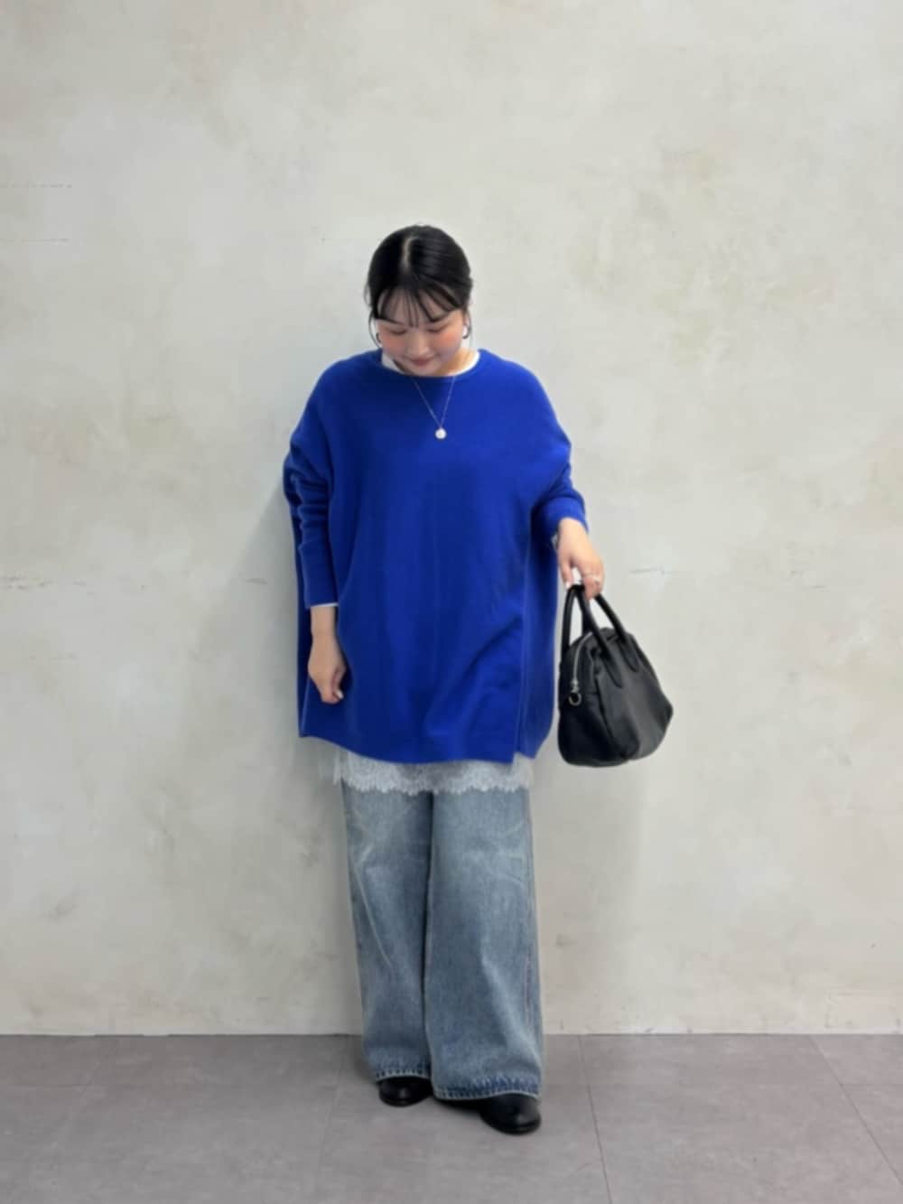 ブルー系のデニムパンツ、ブルー系のニット/セーター、ホワイト系のTシャツ/カットソーを着用したレディースの秋コーディネートの2枚目の写真