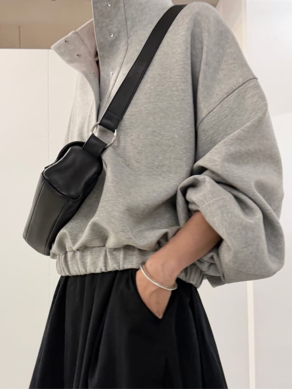 ブラック系のショルダーバッグ、ブラック系のスカート、グレー系のTシャツ/カットソーを着用したレディースの夏コーディネートの7枚目の写真