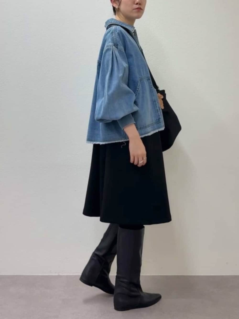 ブルー系のデニムジャケット、ブラック系のワンピース、ブラック系のトートバッグを着用したレディースの冬コーディネートの4枚目の写真