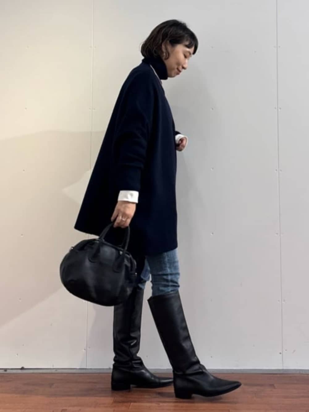 ブルー系のデニムパンツ、ブラック系のトートバッグ、ブルー系のニット/セーターを着用したレディースの秋コーディネートの6枚目の写真
