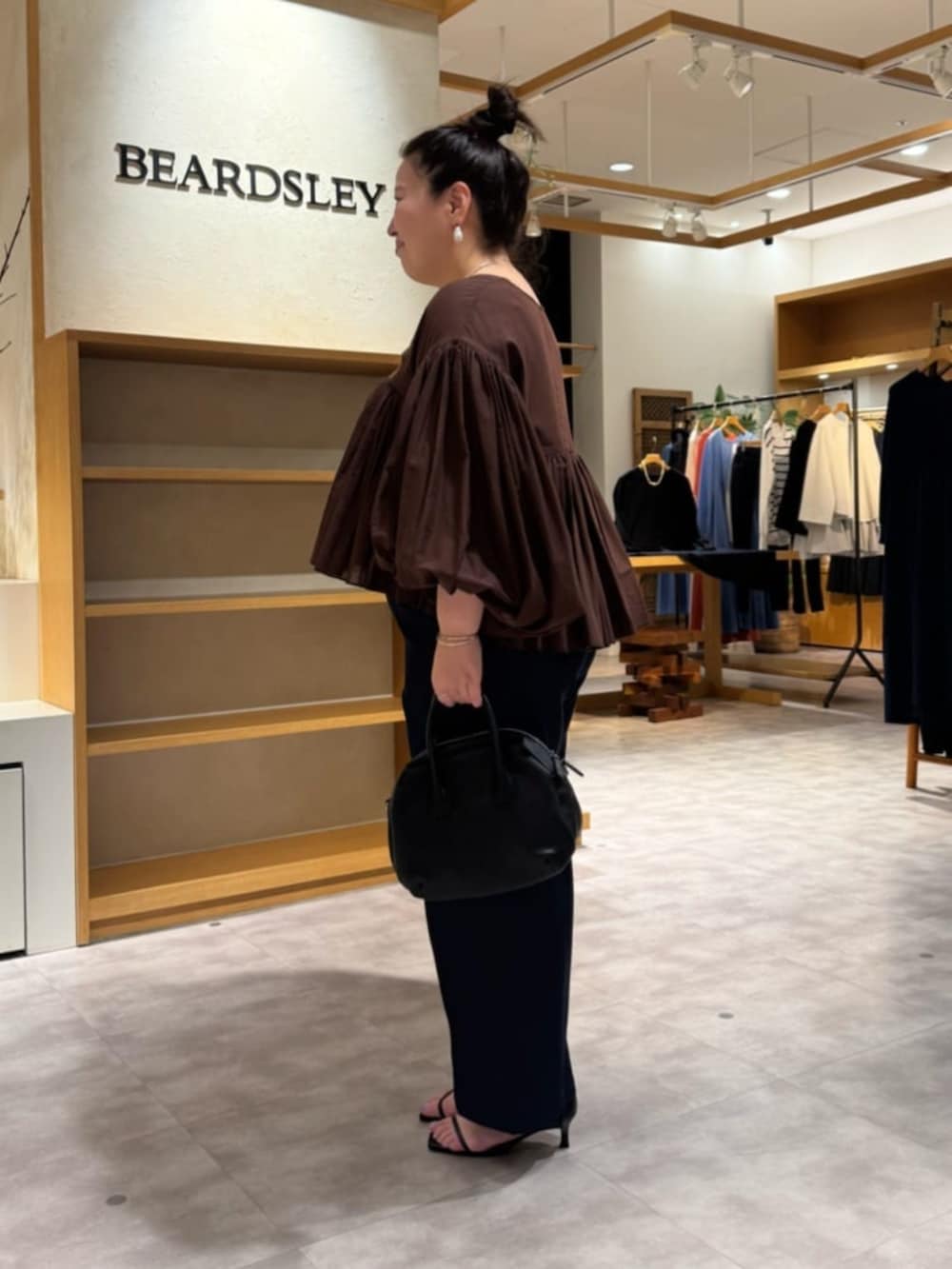 ブラック系のボストンバッグ、ブルー系のその他パンツ、ブラウン系のシャツ/ブラウスを着用したレディースの冬コーディネートの4枚目の写真